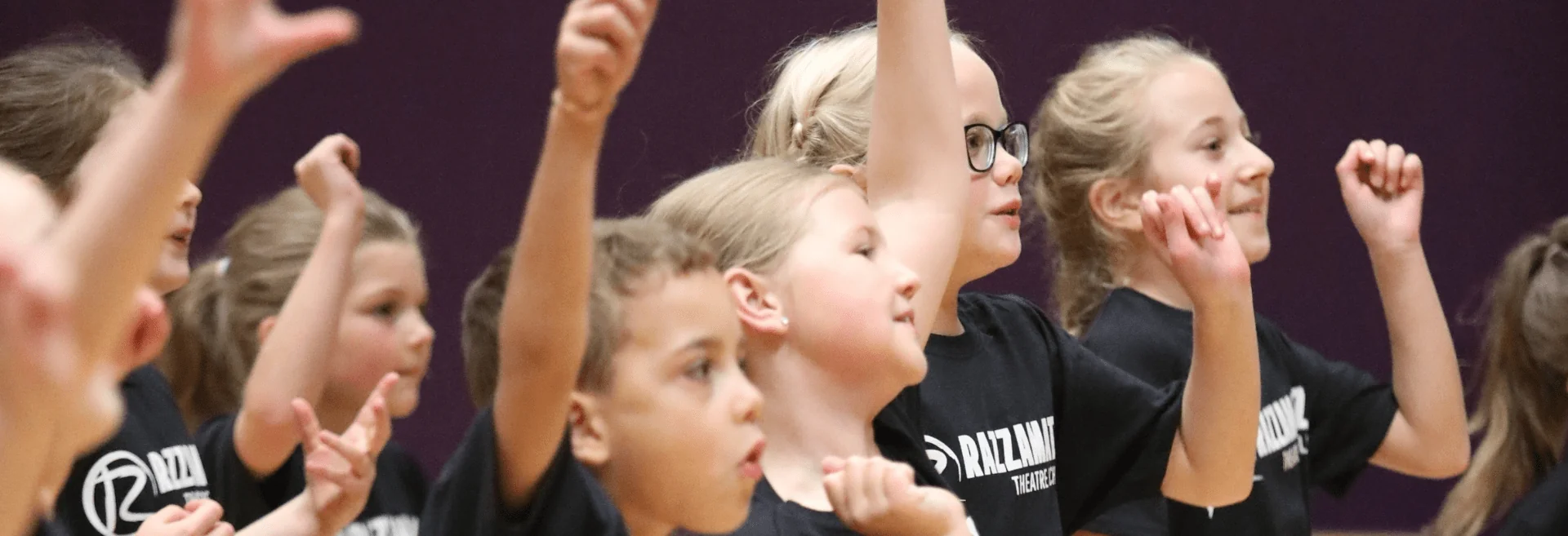 Razzamataz students with arms in the air dancing